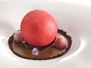 Iced sphere of red fruit on tea cream with crystallized raspberries